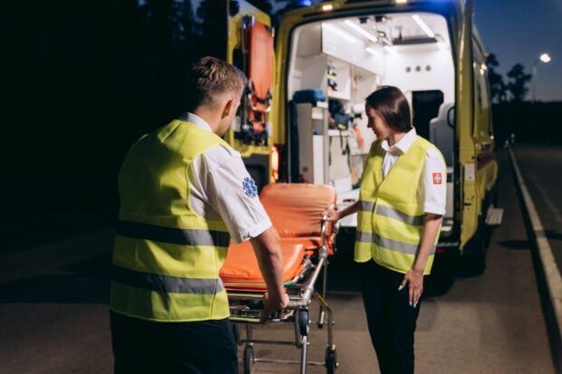 Deux secouristes se tenant près d'un brancard à l'extérieur d'une ambulance de nuit