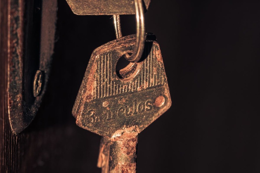 Clés métalliques rouillées insérées dans une serrure de porte en bois, marquées par la corrosion