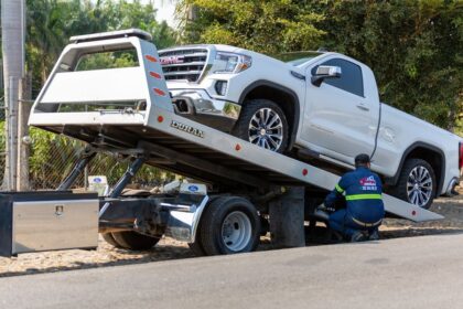 Un opérateur de dépanneuse charge un véhicule utilitaire blanc sur un camion de remorquage