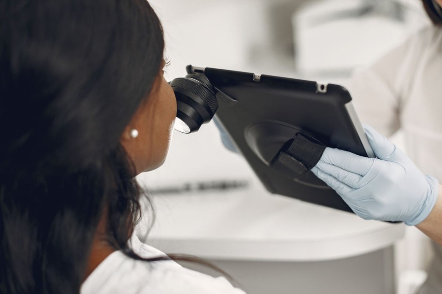 Dermatologue examinant la peau d'un patient à l'aide d'un dermatoscope numérique et d'une tablette