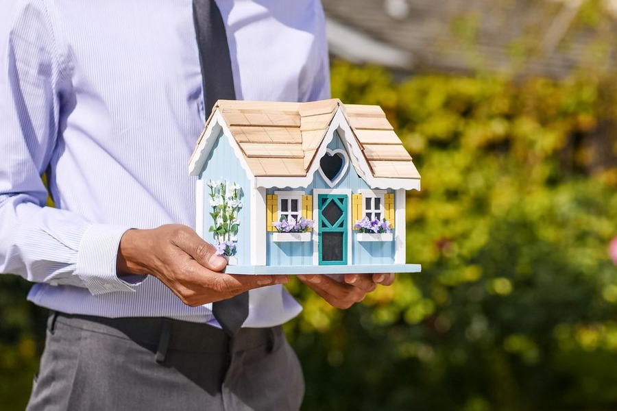 Personne tenant une petite maquette de maison en bois