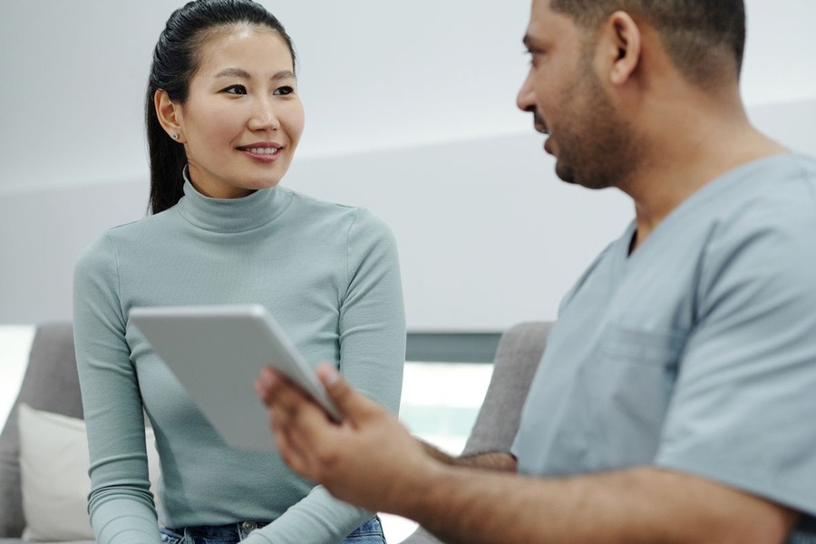 Femme discutant avec un médecin tenant une tablette lors d'une consultation