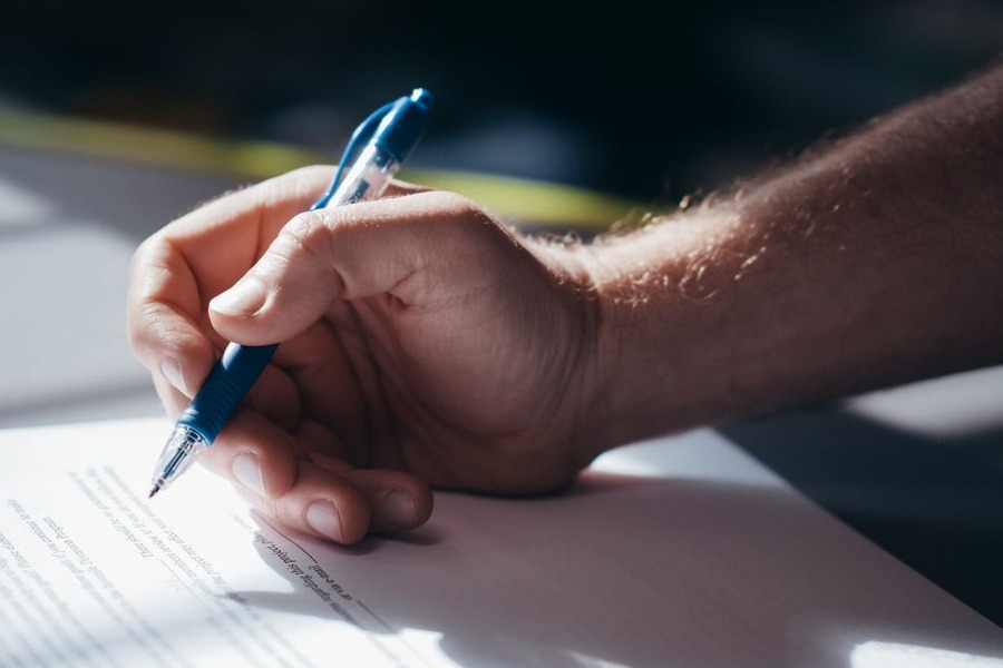 Main signant un document, évoquant les démarches administratives de cession d'un véhicule