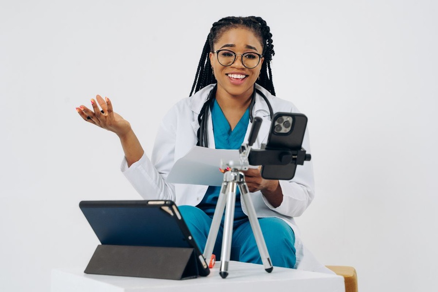 Médecin en blouse utilisant un smartphone et une tablette pour une consultation à distance