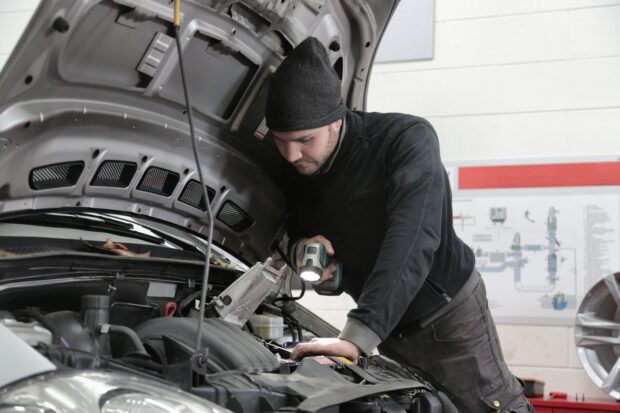 Un homme observe le moteur de sa voiture capot ouvert